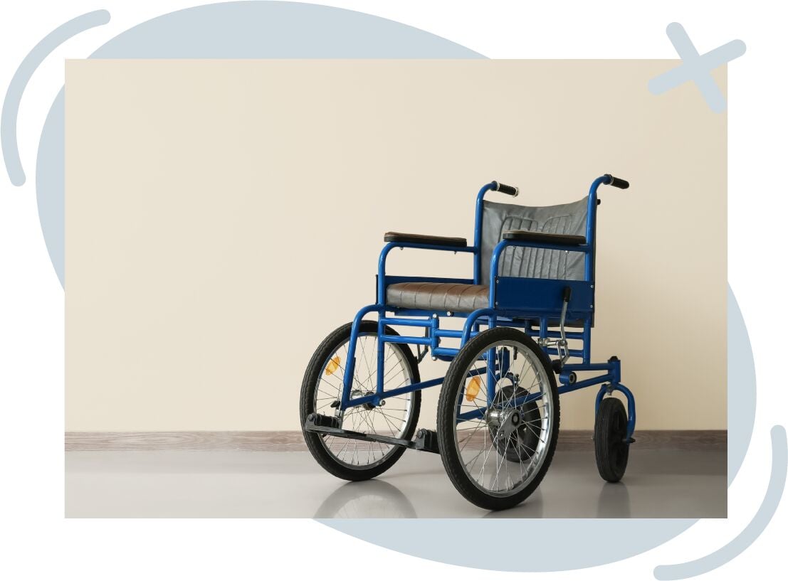 Empty blue manual wheelchair on a smooth floor against a beige wall, photographed at an angle.