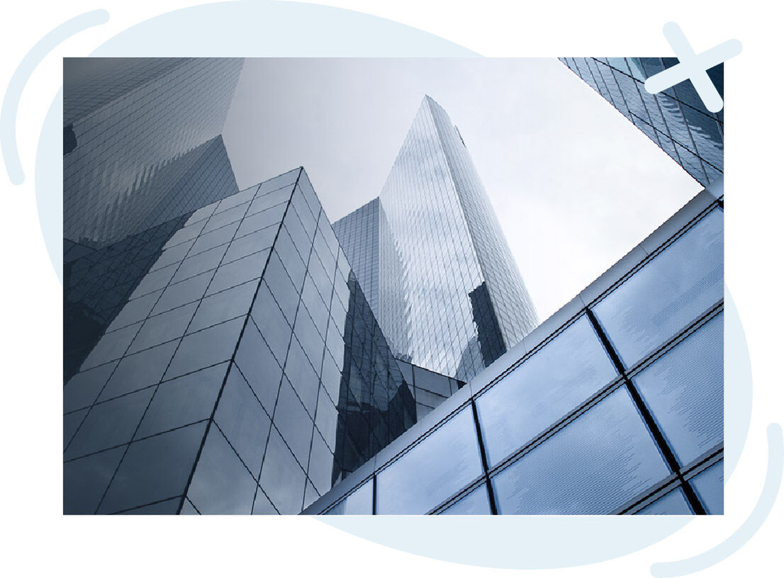 Upward view of modern glass skyscrapers with reflective facades under an overcast sky.