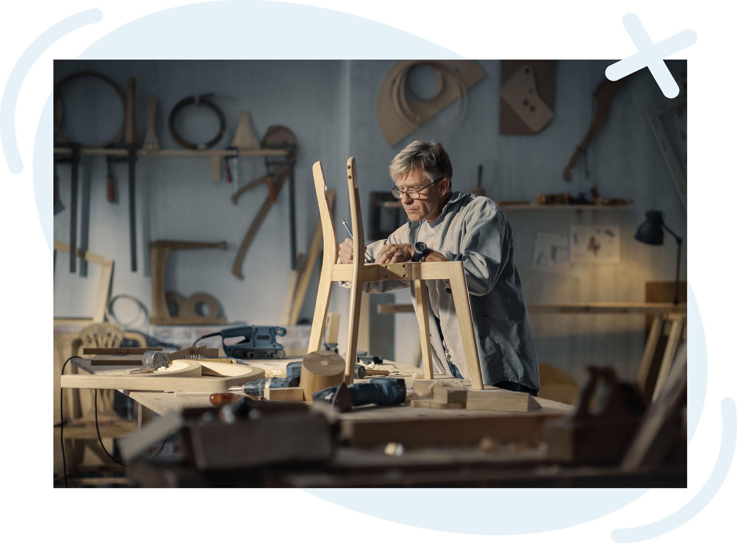 Woodworker concentrating while assembling a wooden chair in a workshop filled with tools and lumber.