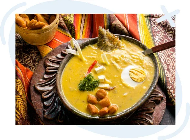 Bowl of traditional Ecuadorian soup garnished with egg, cheese, herbs, and fried dough bites on colorful woven textiles.