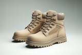 Pair of tan work boots with rugged soles on a neutral background