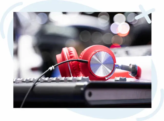 Red on-ear headphones resting on a music keyboard with blurred colorful bokeh lights in the background.