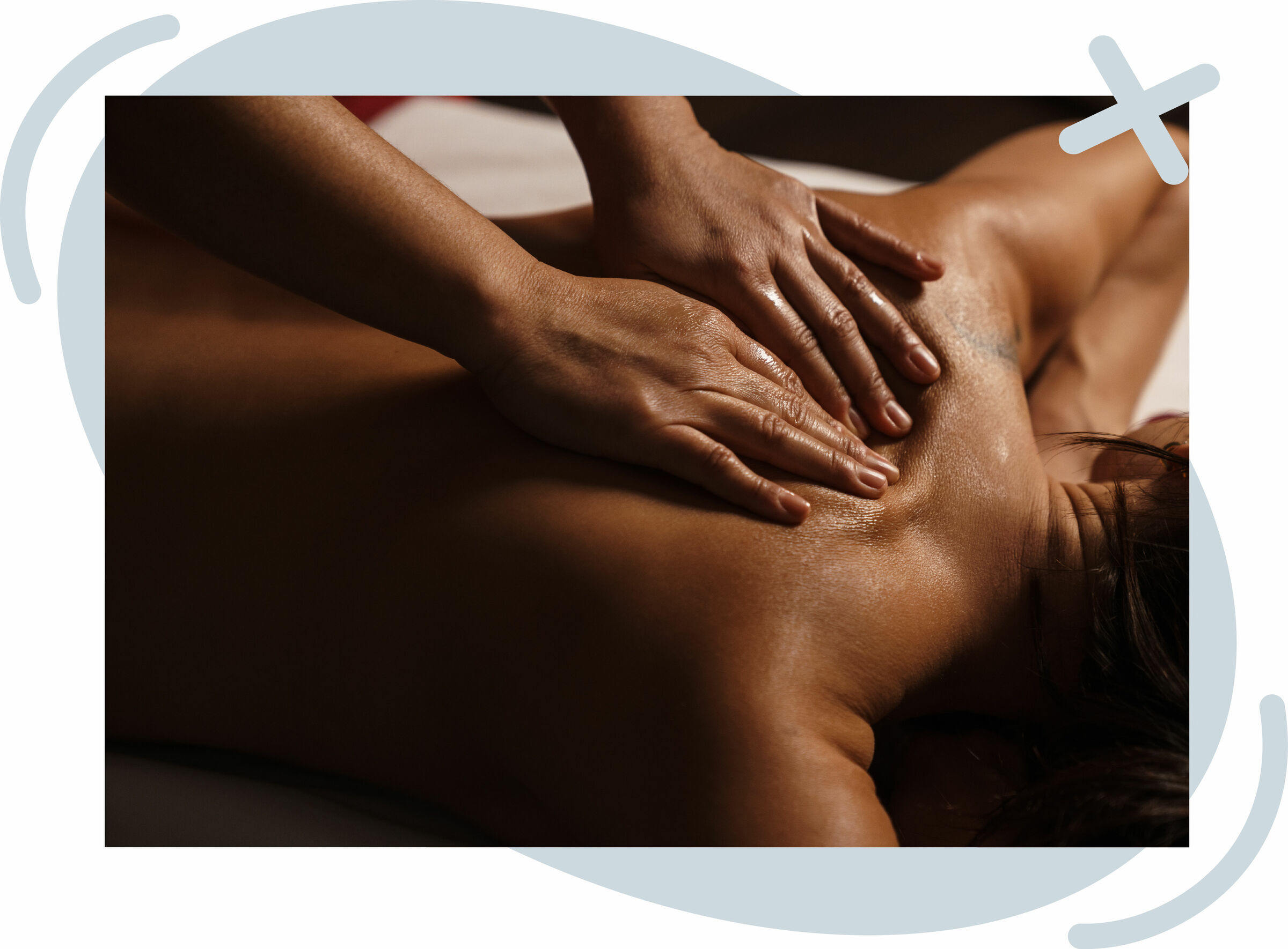 Close-up of a person receiving a back massage, with oiled hands pressing and gliding over the shoulder and upper back in warm, low lighting.