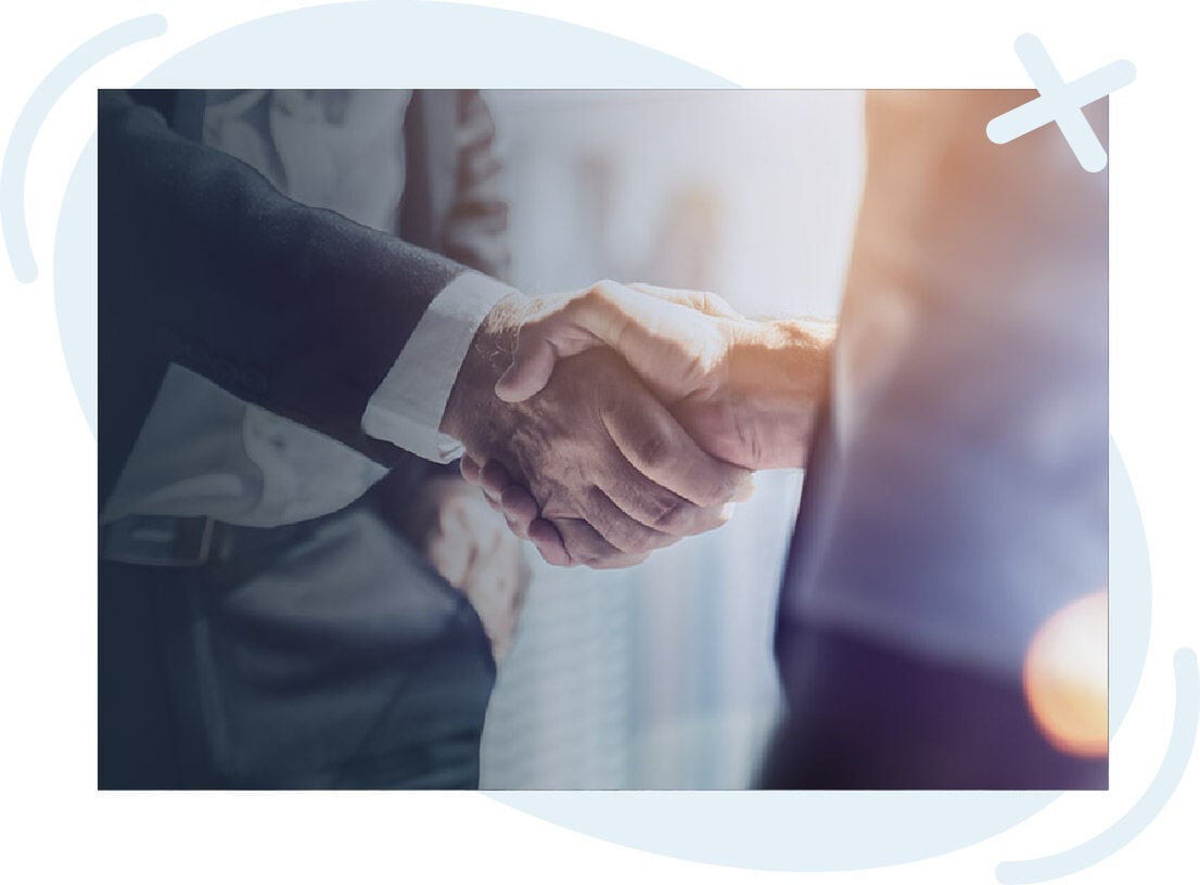 Close-up of two people in business attire shaking hands in a bright office setting.