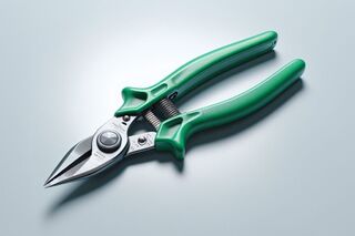 Close-up of green-handled metal snips on a light gray surface