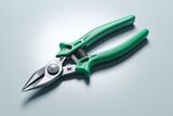 Close-up of green-handled metal snips on a light gray surface