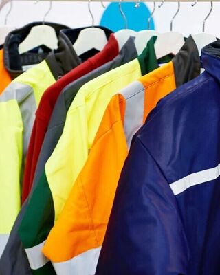 Row of high-visibility work jackets in various colors hanging on a clothing rack.