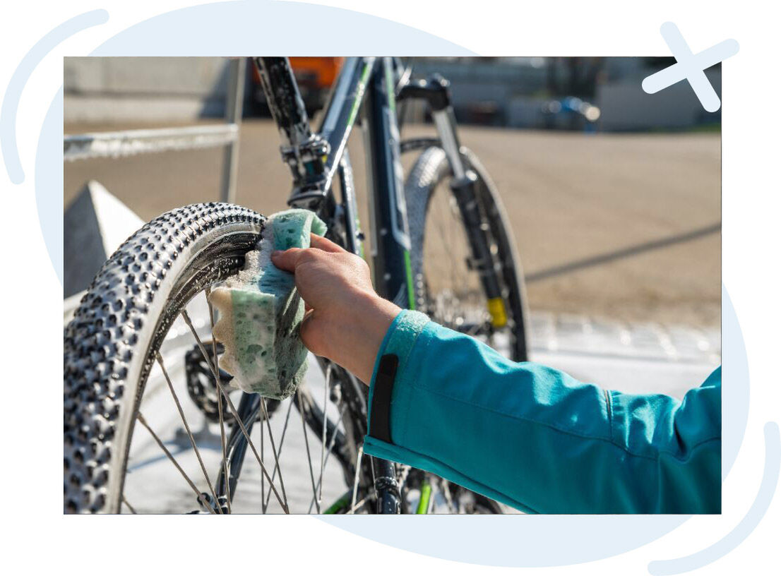 Close-up of a person scrubbing a bicycle tire with a soapy sponge outdoors.