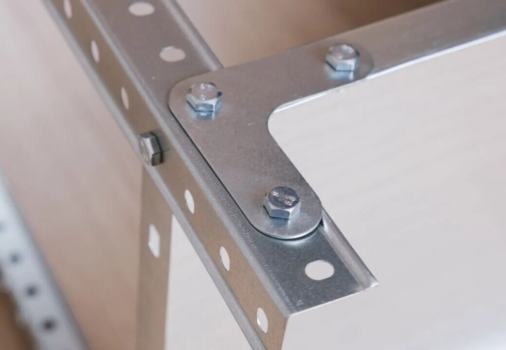 Close-up of a metal corner bracket assembly with bolts fastening perforated steel angles together.