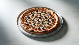 Neapolitan-style pizza topped with tuna chunks and black olives on a marble pizza pan.