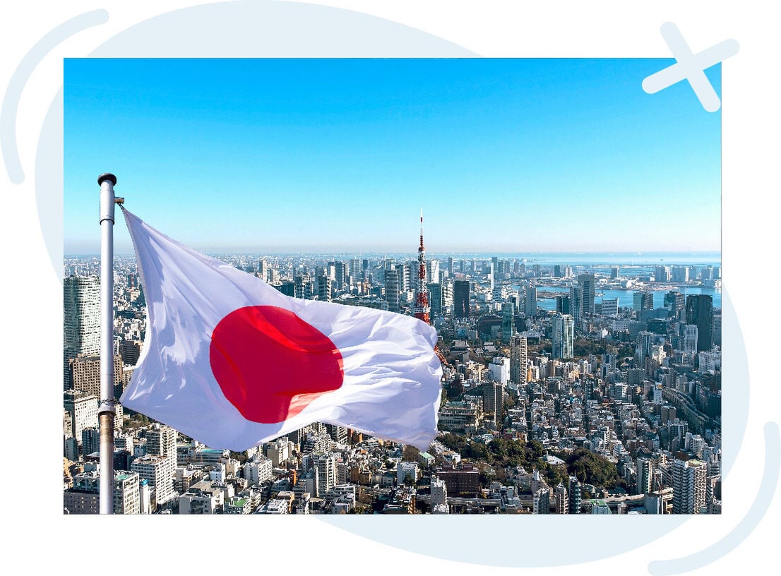 Japanese flag waving above a sprawling modern city skyline on a clear day.