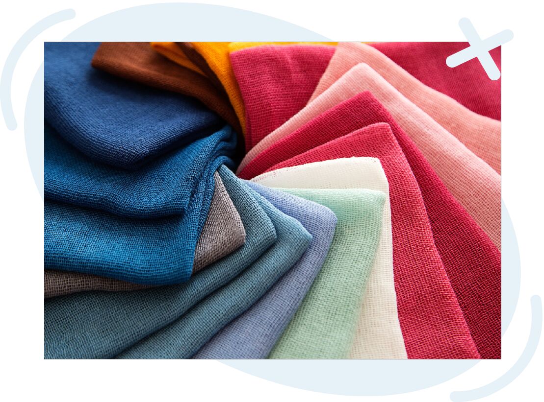 Stacked swatches of loosely woven fabric arranged in a fan, showing a gradient of colors from deep blues and teals to pastels and warm reds and pinks.