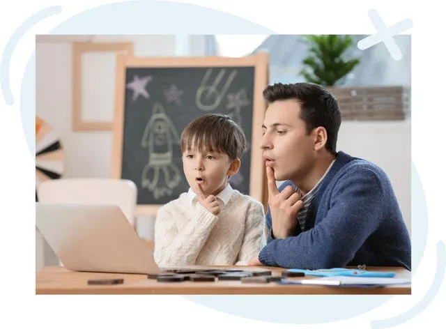 Adult and child practicing speech sounds together while watching a laptop in a classroom setting.