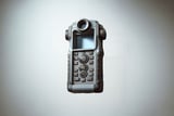 Handheld rugged electronic device with screen, dials, and many buttons, isolated on a light background.