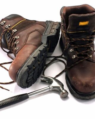 Worn brown work boots with laces and a metal hammer on a white background