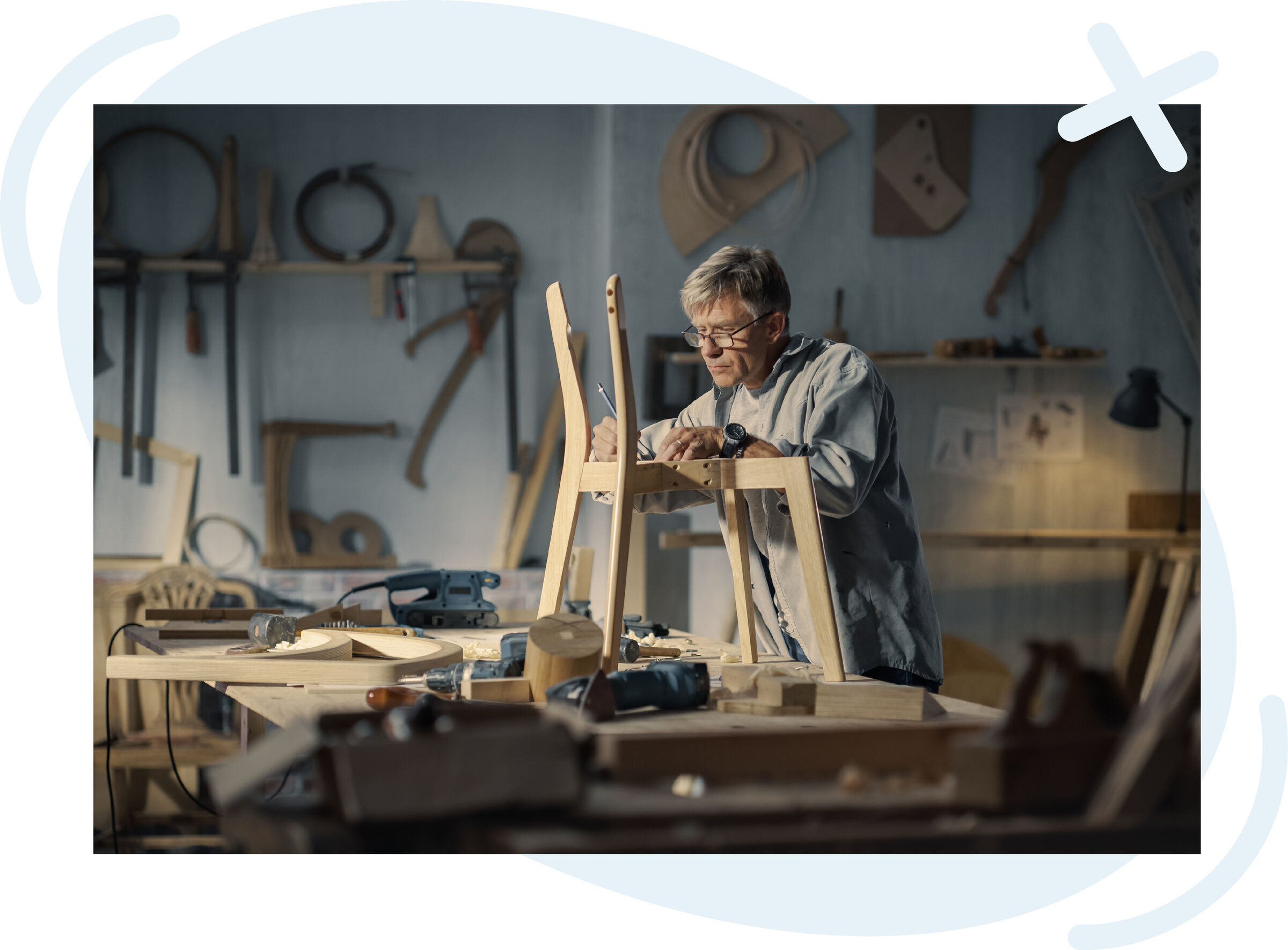 Craftsman in a woodworking studio assembling a wooden chair frame on a workbench.