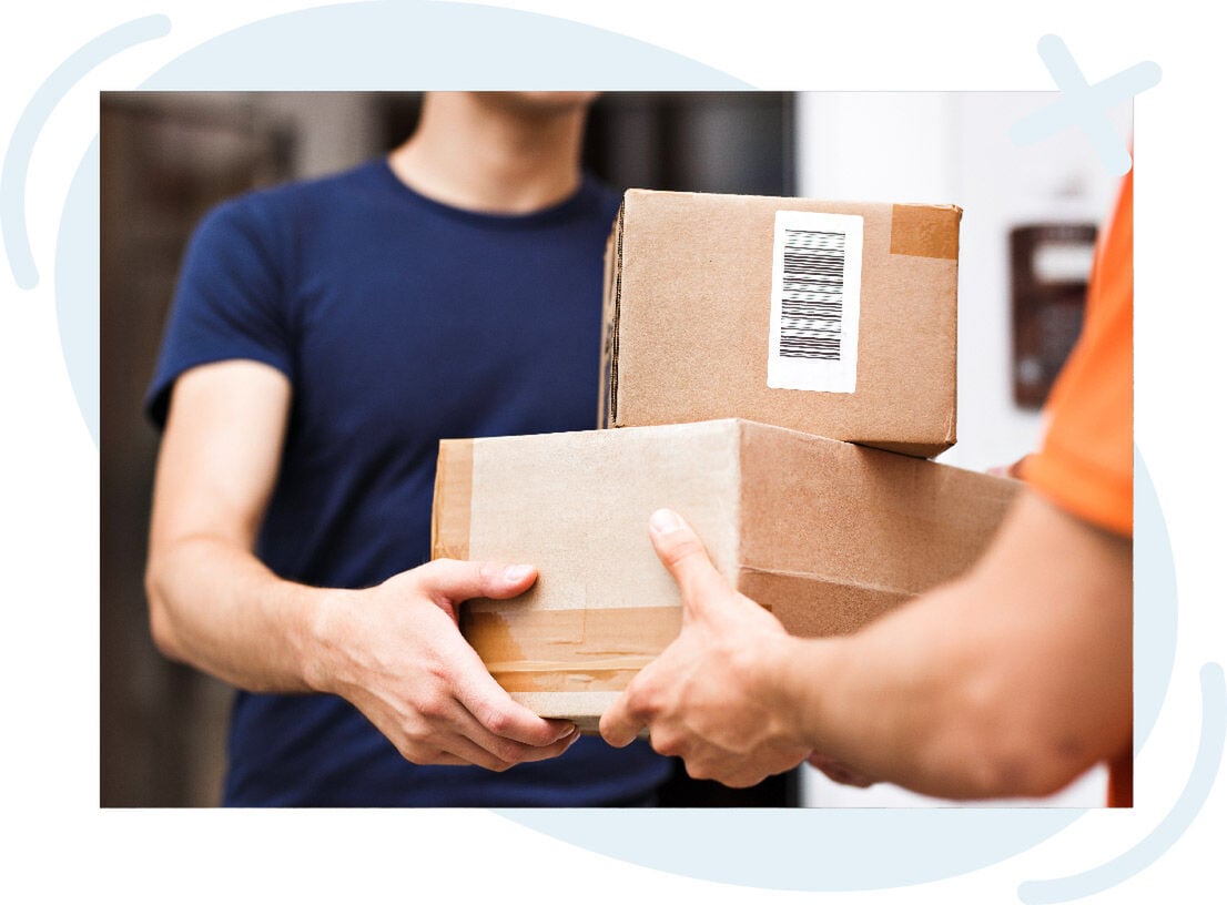 Close-up of a delivery handoff where a courier gives two cardboard packages to a person at the door.