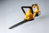 Yellow cordless hedge trimmer with long dual-action blade and black rubberized handles on a light gray background.