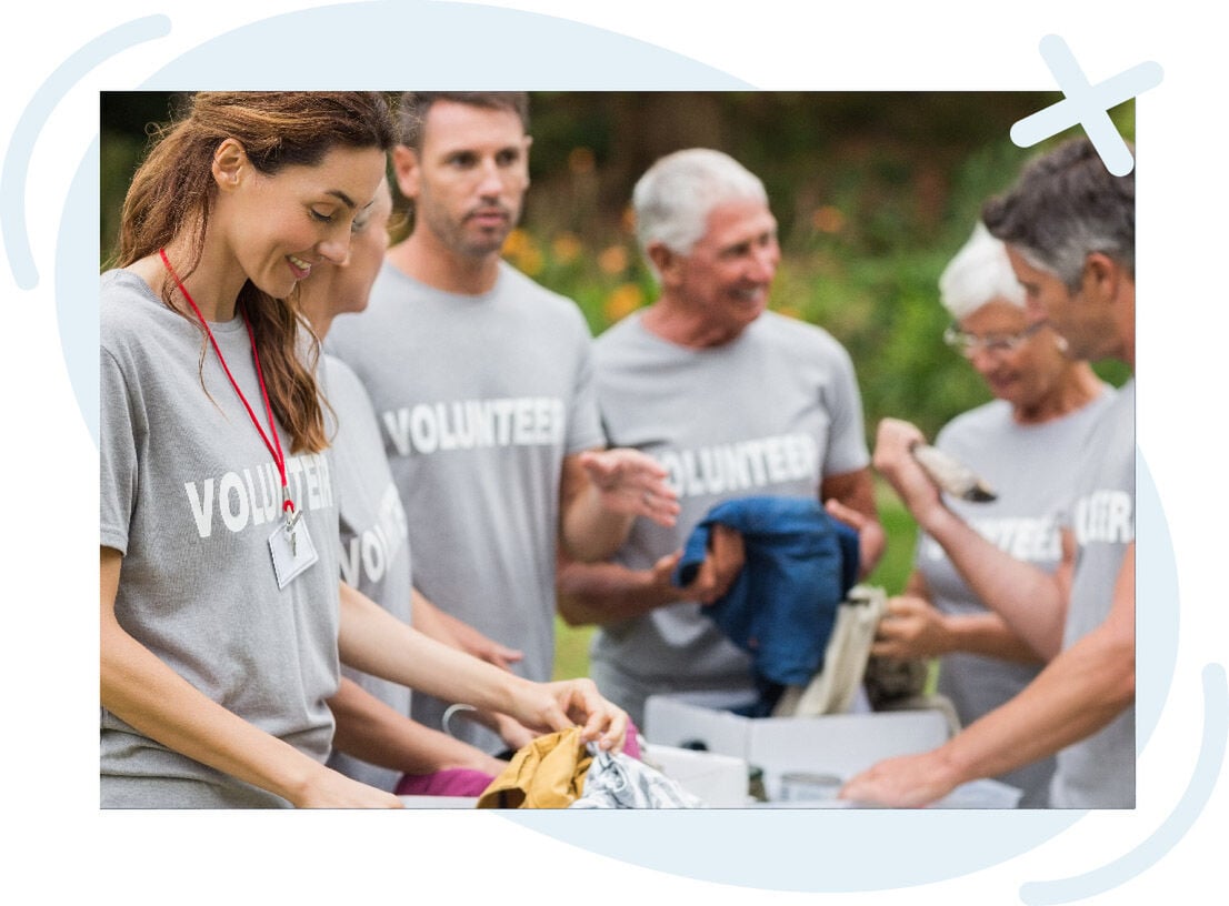 Group of volunteers sorting donated clothing outdoors.