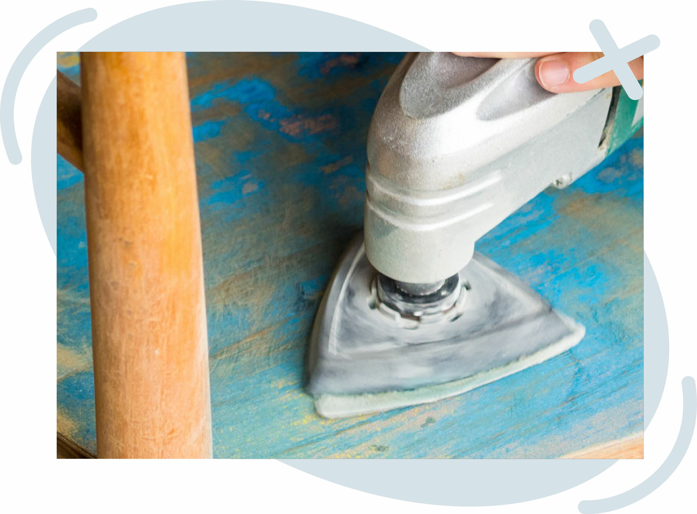 Close-up of a person using a triangular detail sander on a blue-painted wooden surface next to a chair leg.