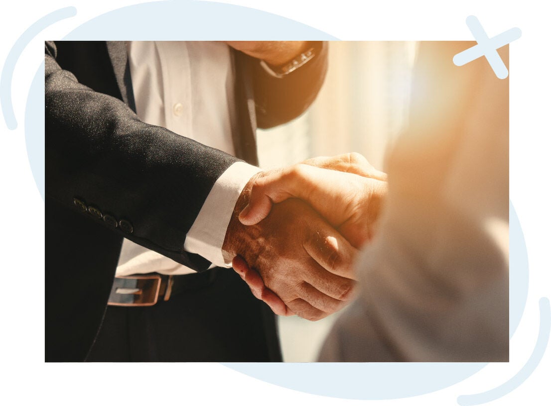 Close-up of two people in business attire shaking hands in warm light.