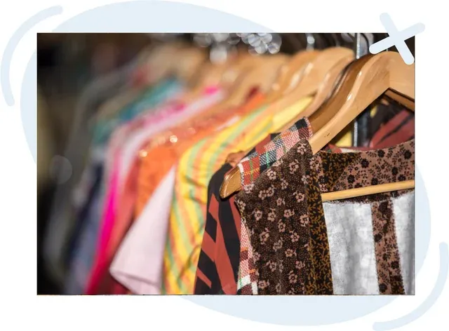 Close-up of assorted colorful clothing on wooden hangers in a thrift or vintage shop rack.