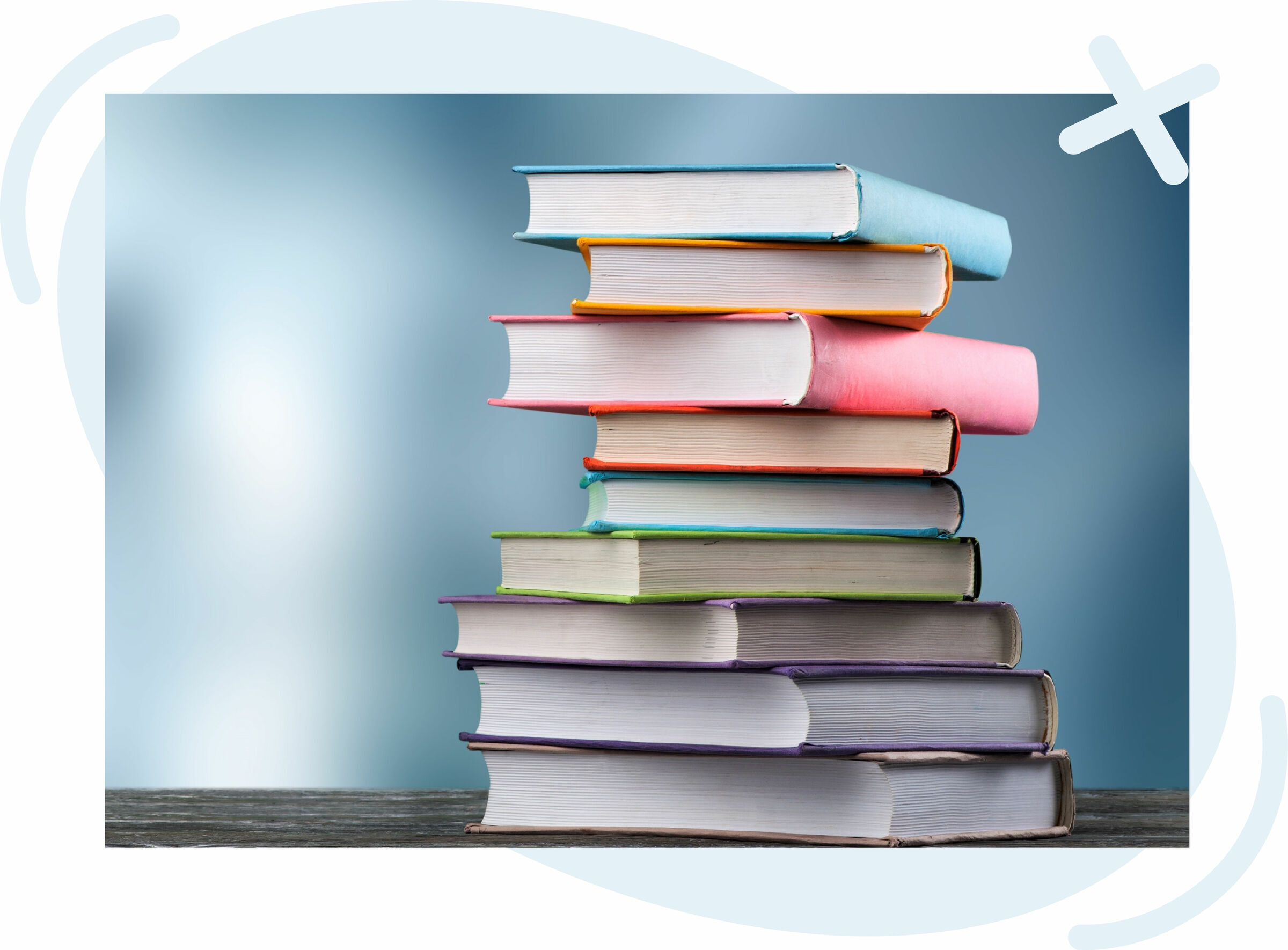 Stack of colorful hardcover books on a wooden surface against a soft blue gradient background.