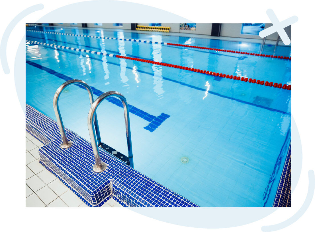 Indoor swimming pool with blue lane lines and a stainless steel ladder at the tiled edge.
