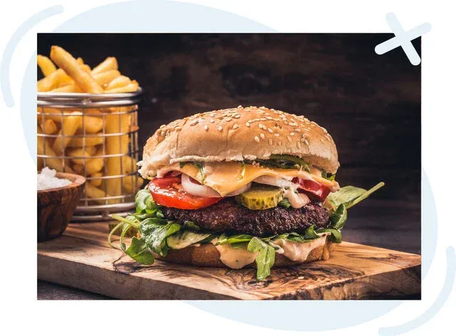 Close-up of a gourmet cheeseburger with fries on a rustic wooden board