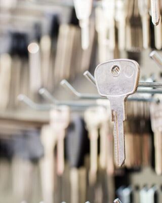 Close-up of a metal key hanging on a display rack among many other keys in a locksmith shop.