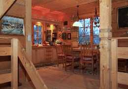 Cozy wooden cabin interior with kitchen and dining area, warm lighting, and rustic decor