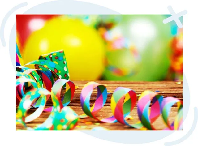 Colorful party scene with curled streamers on a wooden surface and blurred balloons in the background.