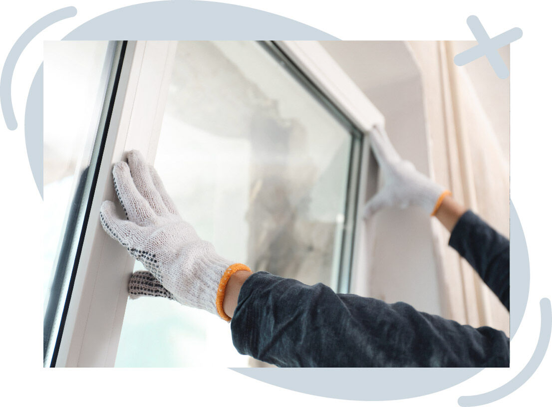 Worker wearing white safety gloves installing or adjusting a white-framed window indoors.