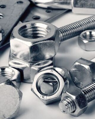 Close-up of assorted metal nuts, bolts, and washers arranged on a surface