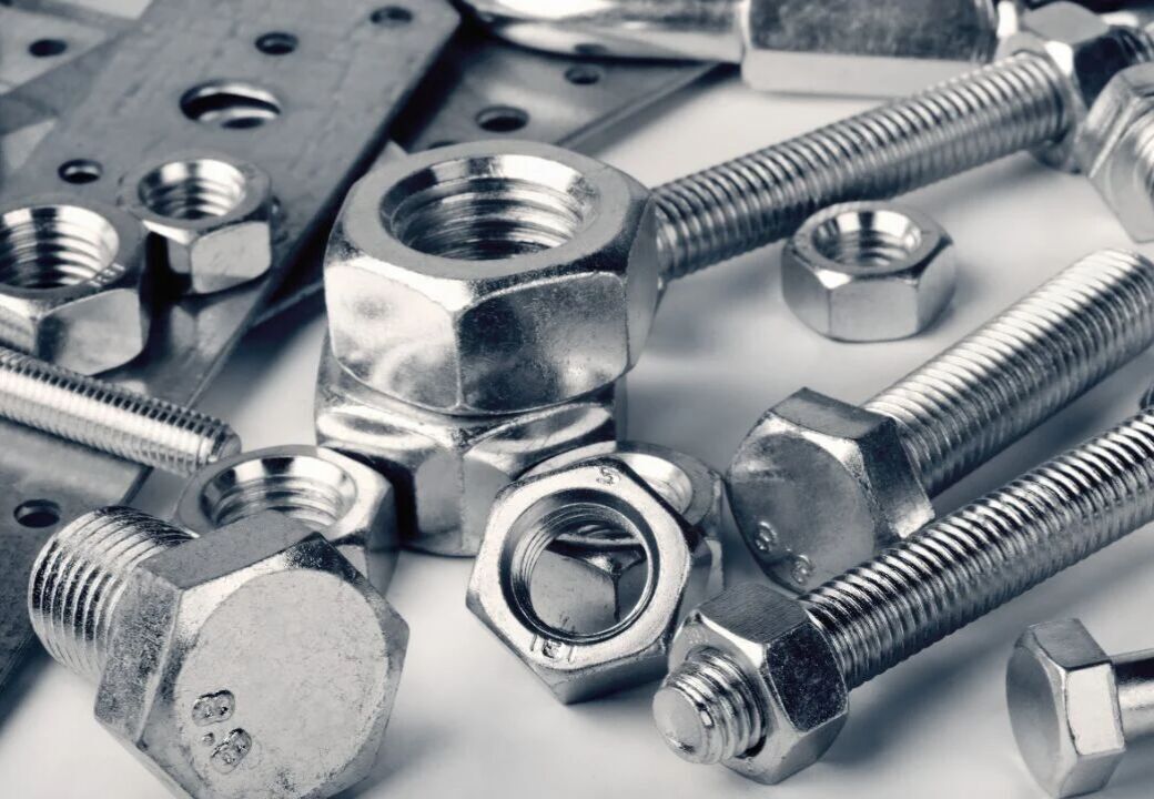 Close-up of assorted metal nuts, bolts, and washers arranged on a surface
