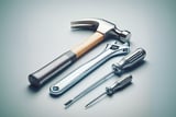 Assorted hand tools including a hammer, adjustable wrench, and two screwdrivers arranged neatly on a smooth surface.