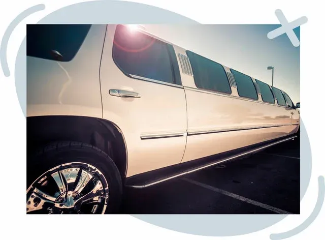 White stretch limousine parked outdoors, viewed from a low angle with sun flare.