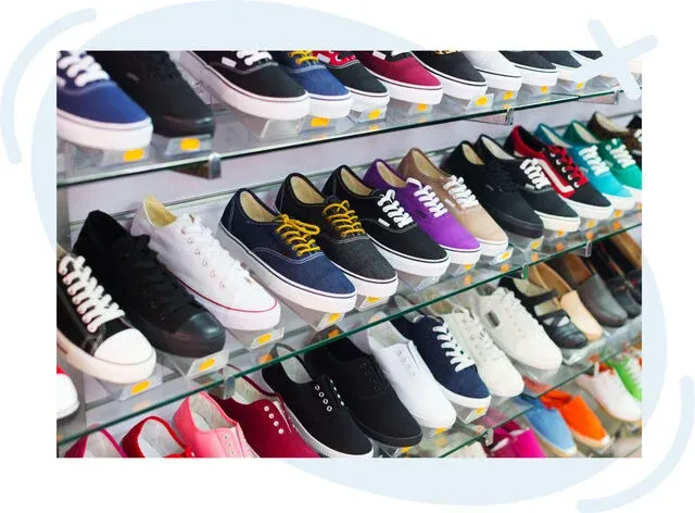 Rows of colorful casual sneakers displayed on glass shelves in a shoe store.