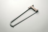 Minimalist photo of a bow saw with a wooden handle and a thin metal frame on a light gray background.