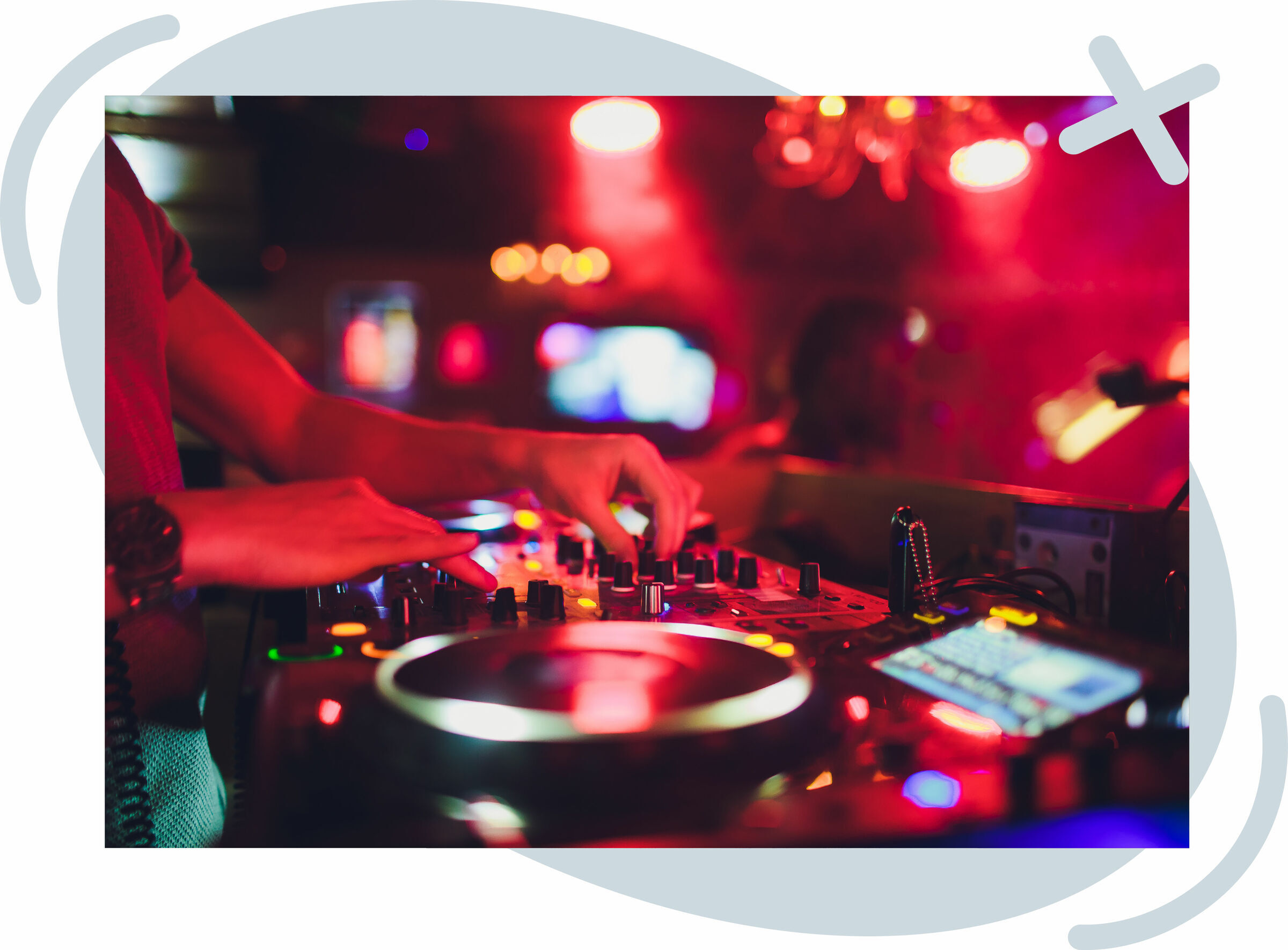 Close-up of a DJ mixing music on a lit-up turntable and mixer in a dim, colorful club.