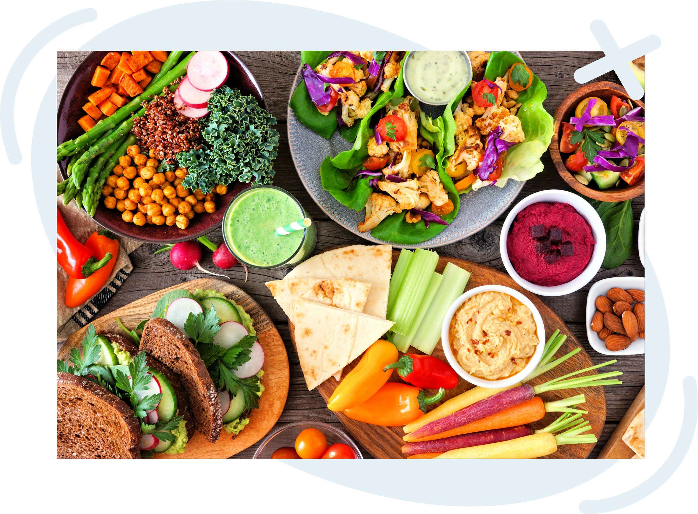 Colorful assortment of healthy plant-based dishes and snacks arranged on a wooden table.
