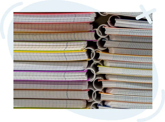 Stacked spiral notebooks with grid paper edges showing colorful separators, viewed from the side.