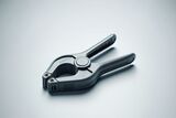 Close-up of a gray plastic spring clamp with textured grips on a smooth light gray surface.