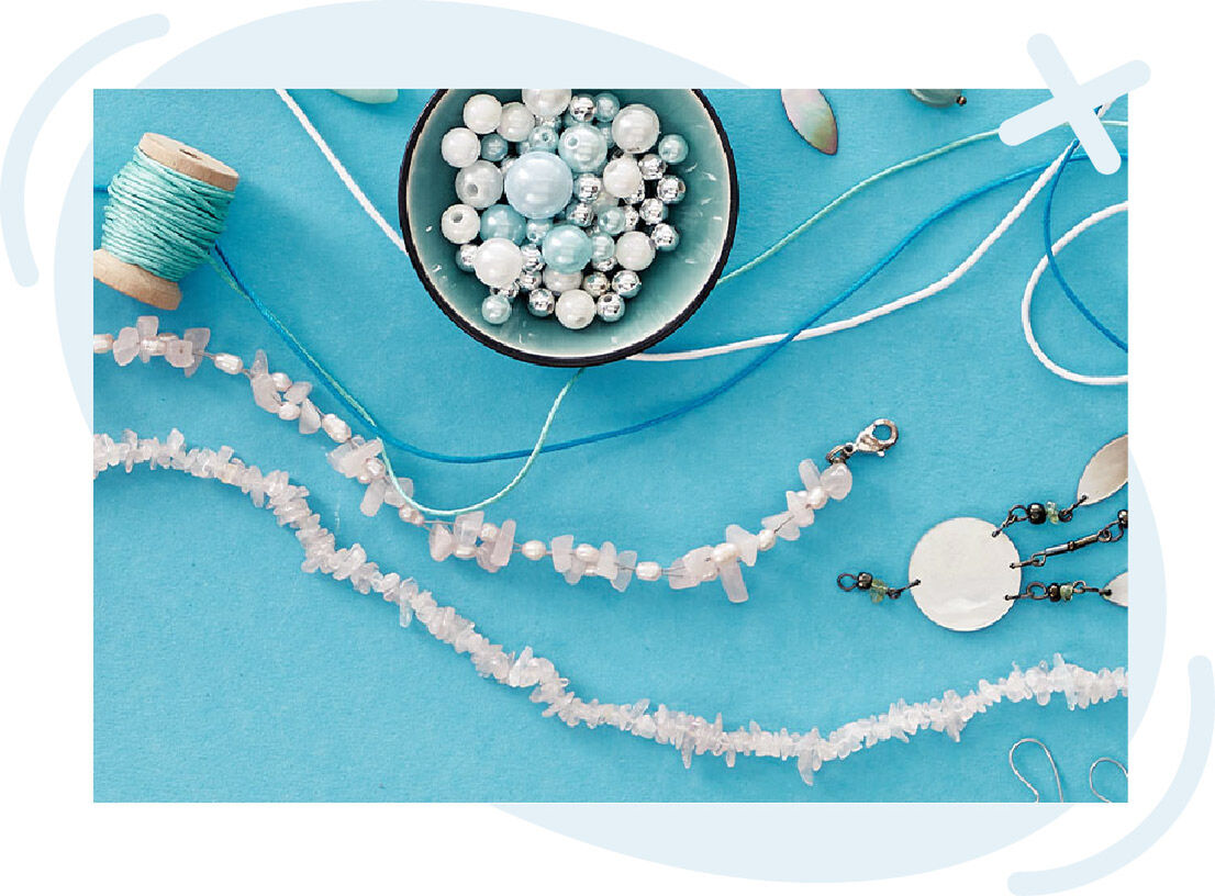 Jewelry-making supplies on a turquoise background, including strings of pale pink stone chips, a bowl of assorted beads, thread spools, and metal findings.