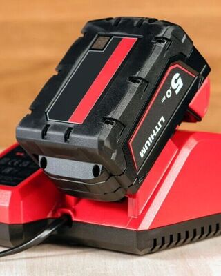 Close-up of a red and black lithium-ion power tool battery on a matching charging base.
