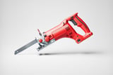 Red handheld reciprocating saw with metal blade and ergonomic grip on a light gray background.