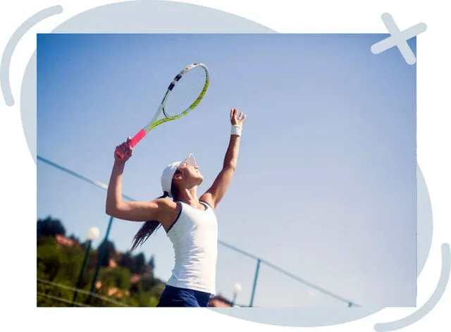 Tennis player tossing the ball and preparing to serve on an outdoor court under a clear blue sky.