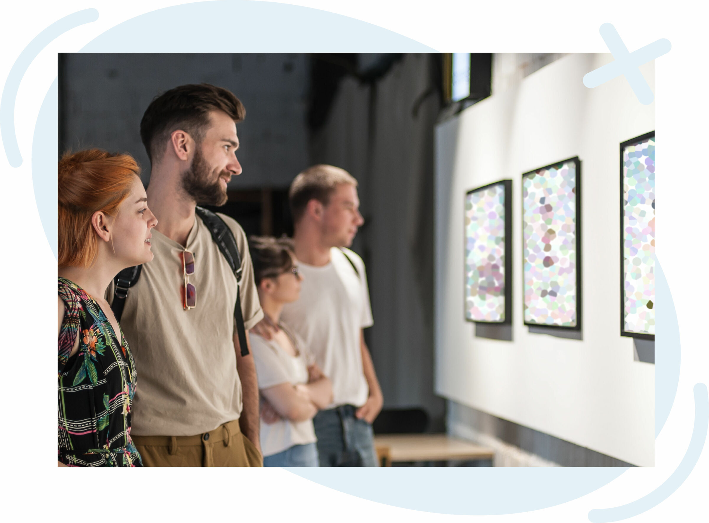 Group of people viewing framed artworks on a white gallery wall.