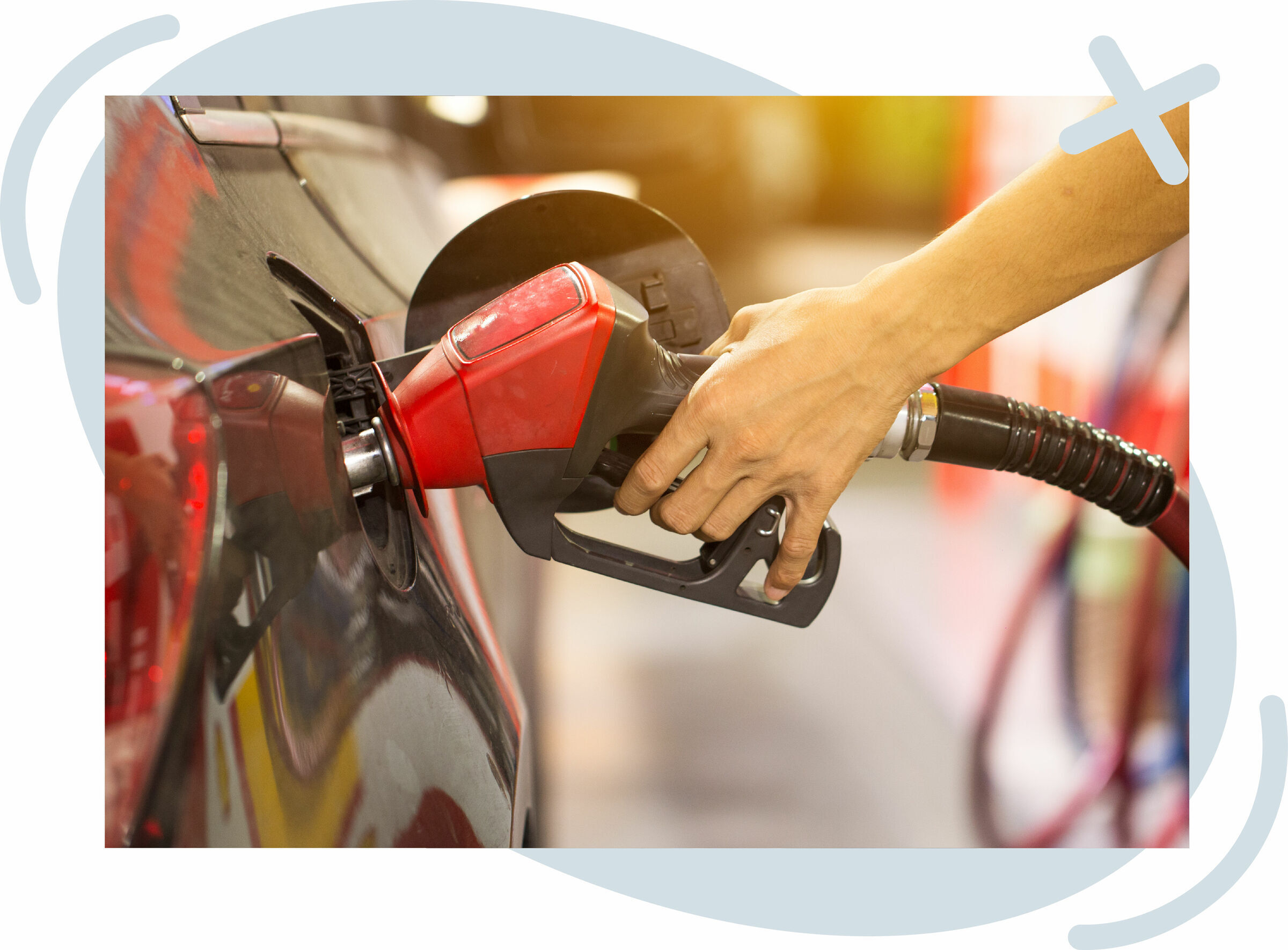 Close-up of a person refueling a car with a red gas pump nozzle at a station.