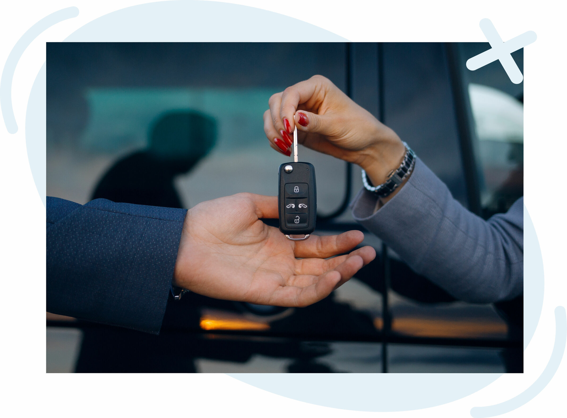 Close-up of a person handing over a car key fob to another person near a vehicle.
